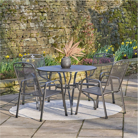 Savoy 4 Seater Dining Set in grey mesh steel with a round 57cm table and four stacking mesh chairs, set on a patio against a stone wall.