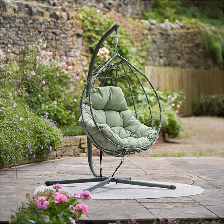 Lyon Moss Green Outdoor Single Hanging Chair on a curved grey steel stand with woven teardrop frame and green cushioned seat, shown on a garden patio.
