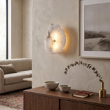 Frammenta LED 1 Light Fragment Alabaster Wall Light with brass centre fixing, shown glowing on a plastered wall above a wooden sideboard in a living room.