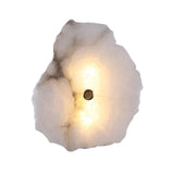 Frammenta LED 1 Light Wall Light with a raw-edged alabaster slab in white and grey tones, lit from within, fixed by a central brass boss, on a plain background.