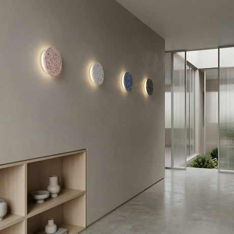 A minimalist hallway features four Pin LED Wall Lights in different colors, a light wood shelf with ceramic vases, and floor-to-ceiling glass doors that flood the space with natural light.