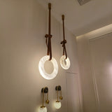 Cintura LED alabaster ring chandelier in warm white, two sizes shown suspended from brown leather straps with copper fittings above a hallway sconce.