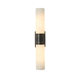 The Velaris 2 Light Double Alabaster Wall Light in soft white and black features a modern design with cylindrical alabaster shades, a central black mount, subtle gold accents, and emits a gentle, warm glow.
