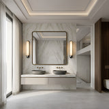 Modern bathroom with a marble accent wall, double gray stone sinks, large mirror, and minimalist lighting, featuring the Lunaris LED Vertical Alabaster Wall Light in Soft White & Black. Sheer curtains let in natural light for an airy atmosphere.