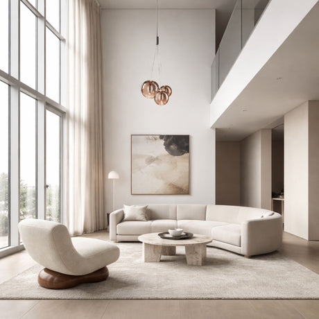 A spacious, modern living room with large windows, neutral-toned furniture including a curved sofa, lounge chair, round coffee table, abstract wall art, and the Diverso LED Pendant Light in copper. Natural light fills the space.