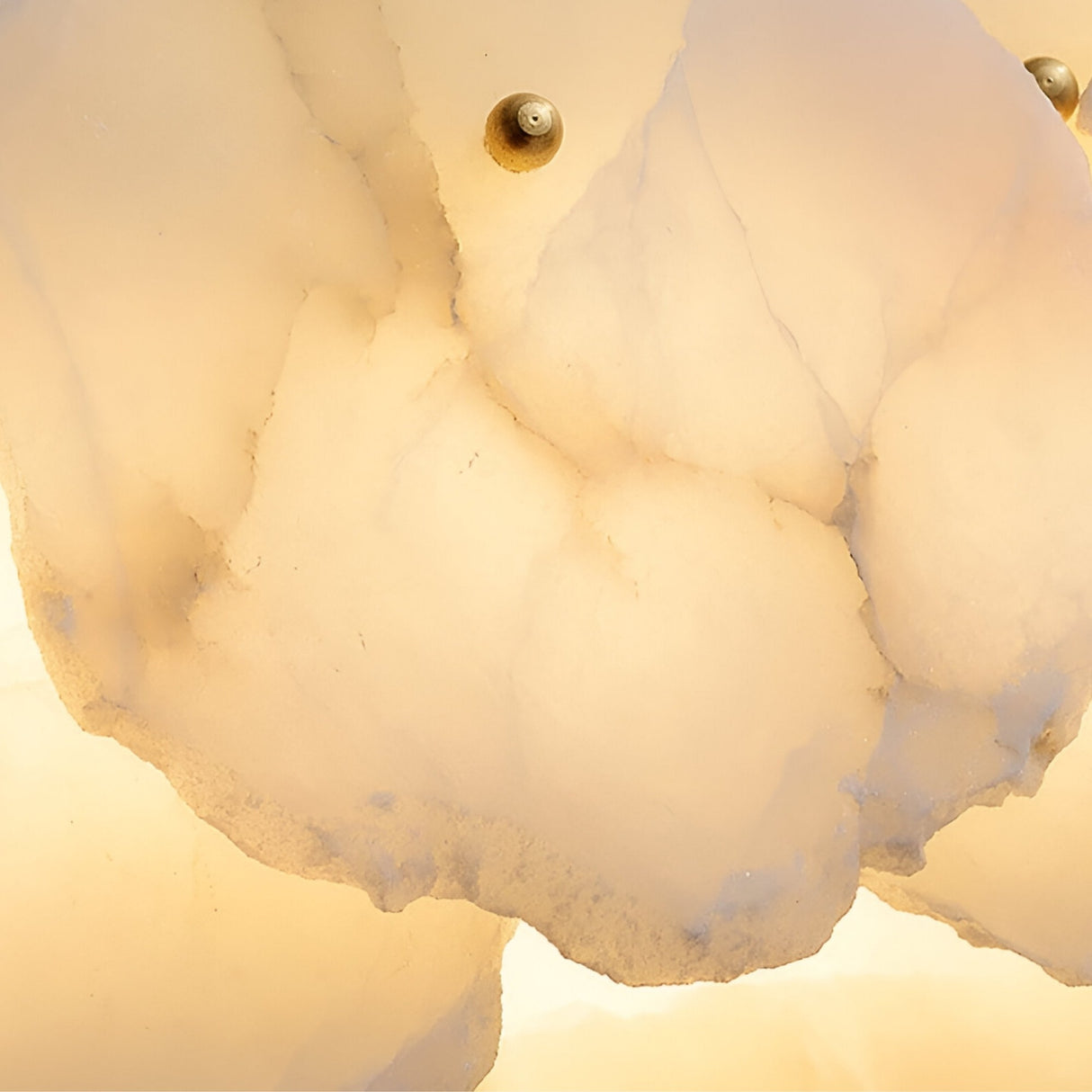 Close-up of layered, translucent alabaster with soft, warm lighting and two small brass fasteners shows the elegant textures and cloudy patterns of the Solvane LED Small Petal Alabaster Chandelier in Soft White & Brass.