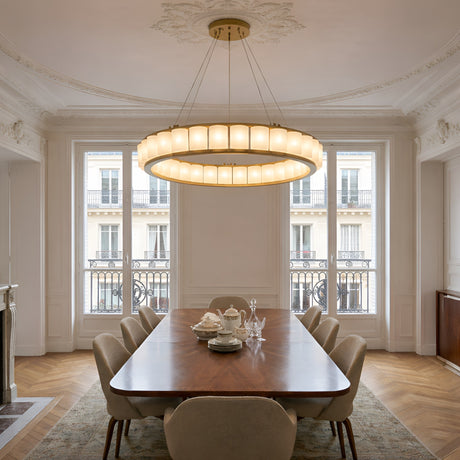 Elegant dining room with a large wooden table, beige chairs, ornate ceiling, and the Orion 27 Light Ring Alabaster Chandelier in soft white & brushed brass. Tall windows with decorative railings reveal classic facades and fill the space with natural light.