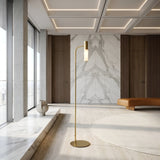 A modern minimalist interior with marble floors and walls, a Magari Floor Lamp - Gold, a low tan bench, wooden wall panels, and large floor-to-ceiling windows with city views.