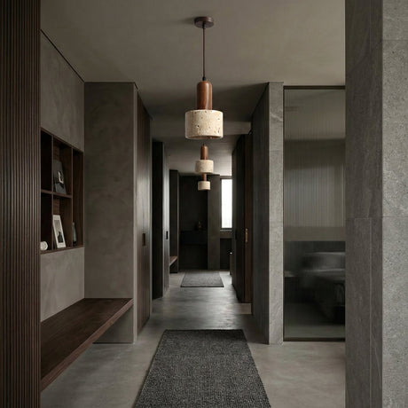 A modern hallway with gray walls and floors, minimal walnut brown shelves, a built-in bench, a Lunaro 1 Light Small Travertine Single Pendant Light in Walnut Brown & Light Beige, and a textured rug, leading to a sunlit room.