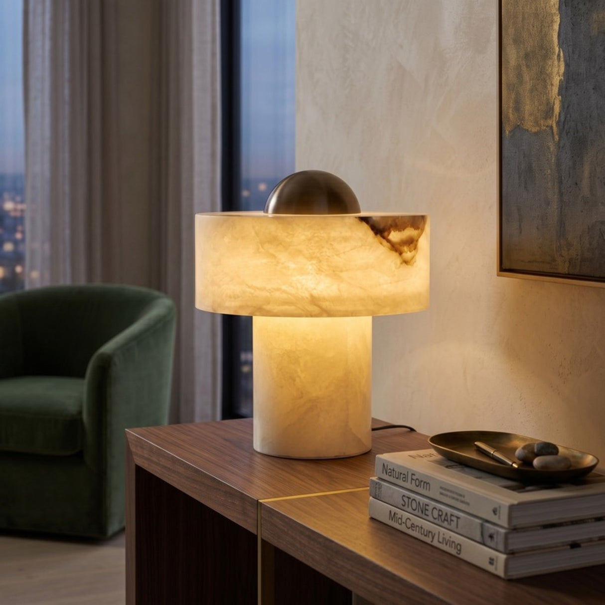 Cupolino Dome Alabaster Table Lamp in white with brass dome top, glowing on a console table beside books in a living room setting.