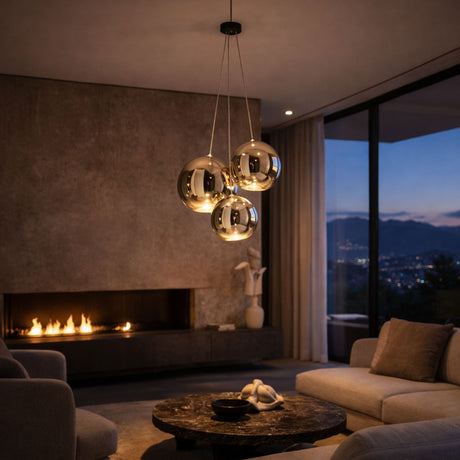 A modern living room with a marble coffee table, beige sofas, a lit fireplace, abstract sculpture, city-view windows at dusk, and three Diverso LED Pendant Lights in gold hanging from the ceiling.