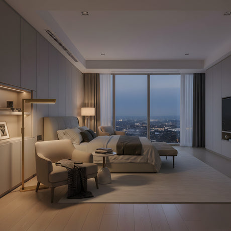 A modern, spacious bedroom features a large bed, an armchair, and the Solin LED Alabaster Floor Lamp – Brushed Brass. Floor-to-ceiling windows showcase a dusk cityscape, while neutral tones and minimalist decor create a serene mood.