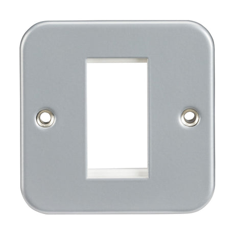 The Metal Clad 1 Gang Modular Faceplate is a rectangular, metallic faceplate designed for wall sockets or switches. It features a central cut-out with two screw holes on opposite sides. Its smooth and reflective surface ensures durable performance, and it is compatible with euro-modules for bespoke solutions.