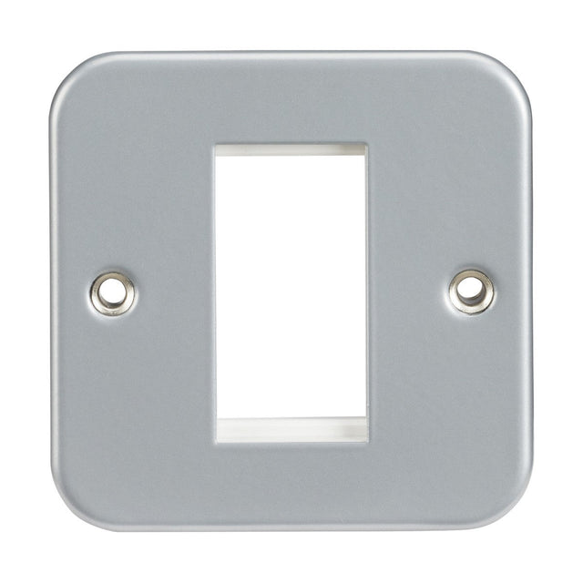 The Metal Clad 1 Gang Modular Faceplate is a rectangular, metallic faceplate designed for wall sockets or switches. It features a central cut-out with two screw holes on opposite sides. Its smooth and reflective surface ensures durable performance, and it is compatible with euro-modules for bespoke solutions.