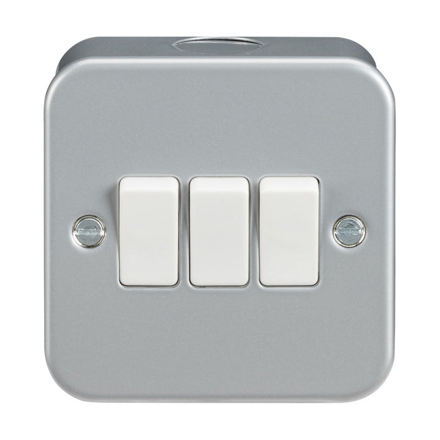 The Metal Clad 10AX 3 Gang 2-Way Switch is a silver, metallic wall-mounted light switch plate featuring three white rocker switches aligned in a row. It boasts a powder-coated surface and includes visible screws on each side for secure mounting, combining durability with style.