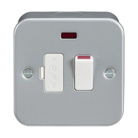 The Metal Clad 13A Switched Fused Spur Unit Neon is a square electrical switch that includes a fuse and two screws, with a neon indicator light positioned at the top. It features a white switched fused spur set against a silver metallic backdrop within a robust metal clad box.