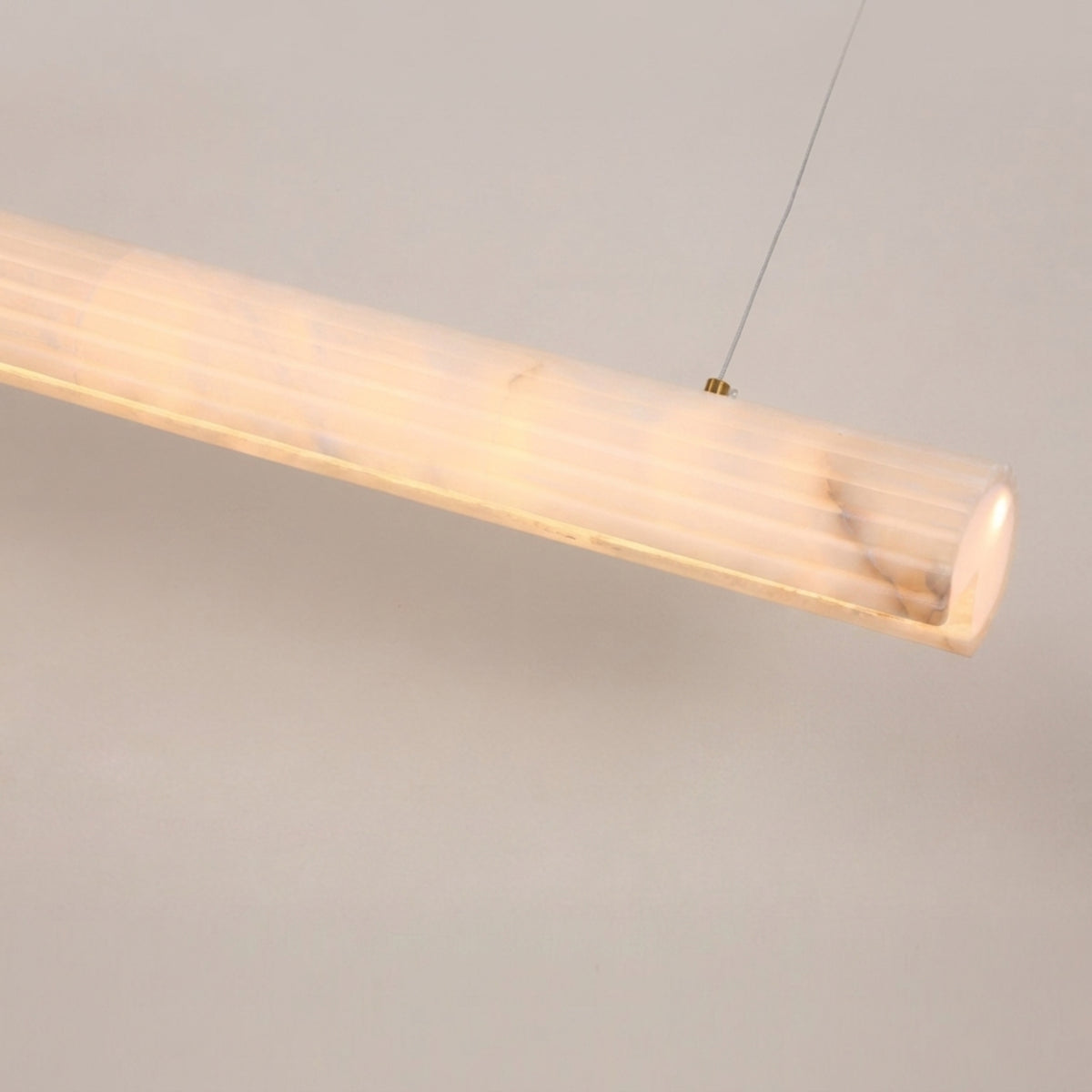 Zenvia LED Alabaster Linear Chandelier in soft white, close-up of the cylindrical natural stone diffuser on a slim cable suspension, shown against a plain light background.