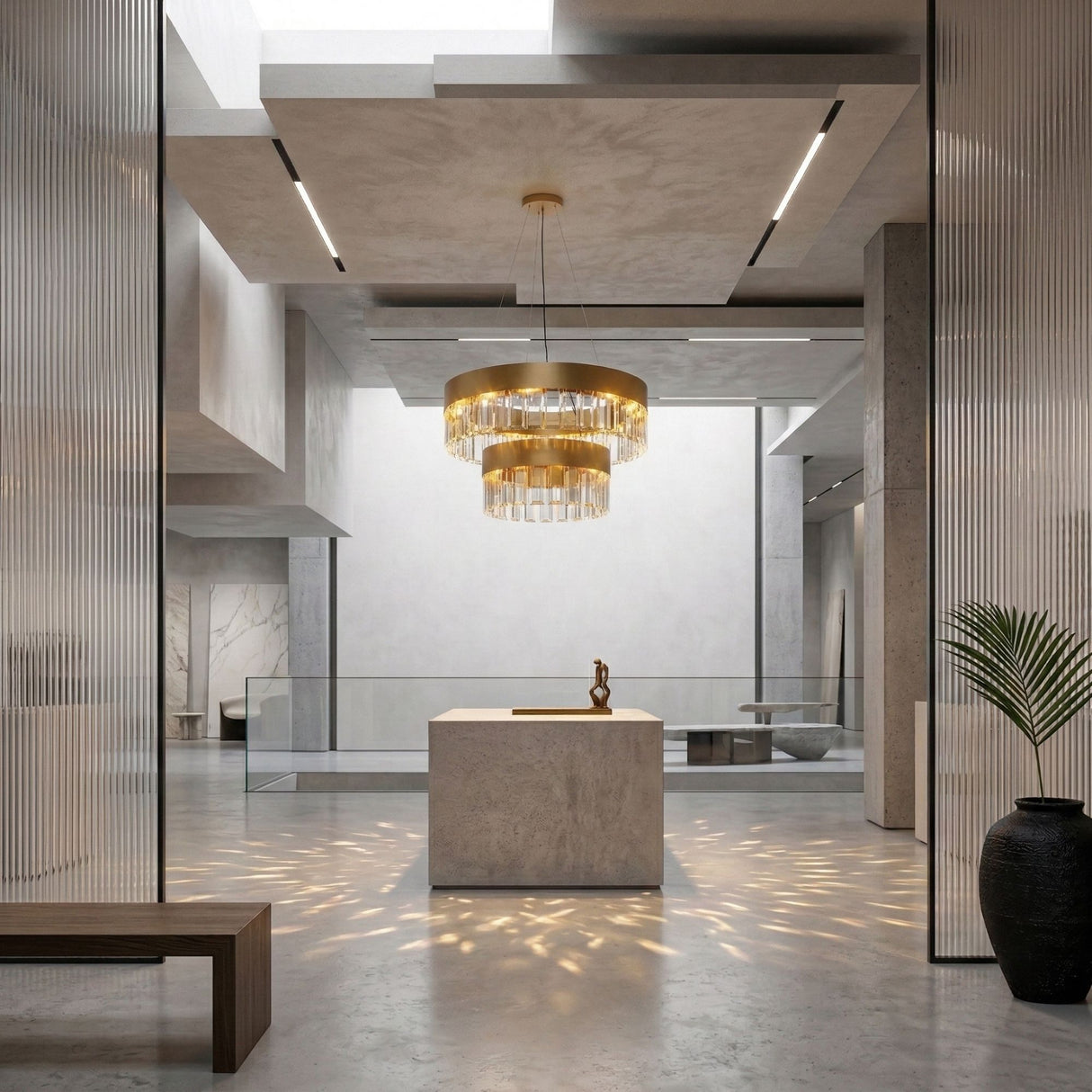 A modern, minimalist interior with concrete floors, a marble island, a Donato 12 Light Crystal Chandelier - Gold, skylight, glass railings, wooden bench, potted plant, and abstract sculpture creates a bright and elegant space.