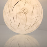 The Lunar Flush Ceiling Light - White features a round, frosted glass shade with soft, grass-like streaks that create a gentle white glow and warm ambient lighting when illuminated.