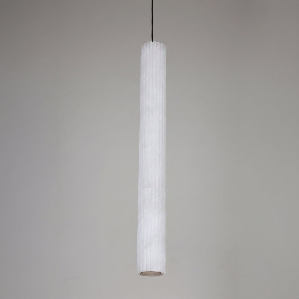 Zenvia LED Alabaster Single Pendant Light with a slim fluted white stone column, brushed brass ceiling cap, and black drop cable against a plain grey background.