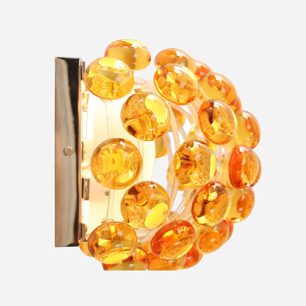 Introducing the Briller LED Small Wall Light - Gold, a wall-mounted fixture boasting a circular design with amber-colored glass discs and a gold finish, complemented by a decorative pattern to enhance its modern aesthetic.