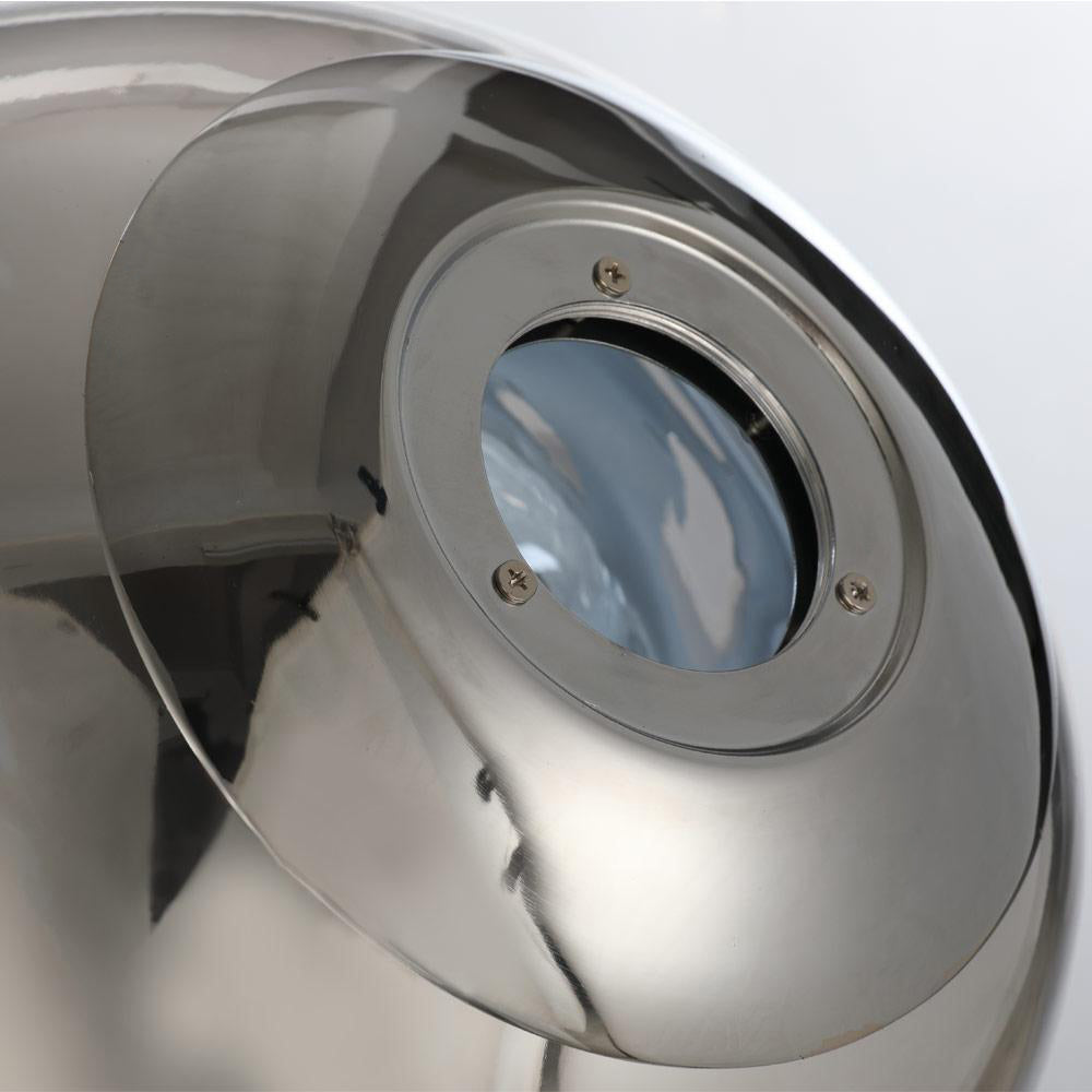 Close-up of a polished stainless steel object with a circular glass window secured by four screws, displaying a reflective surface with subtle molten effects reminiscent of an organic design, against a softly blurred background akin to the glow of the Lava Floor Lamp - Silver.