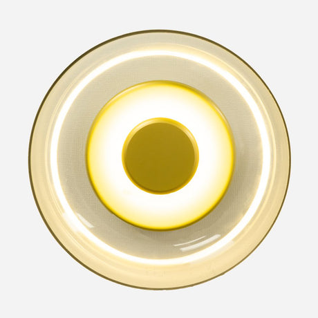 The Blossom LED Glass Wall & Ceiling Light - Gold features a bright central disc with concentric glowing rings, emitting a warm yellow hue for ambient lighting. Its subtle gold finish enhances the elegant, modern design against a plain background.