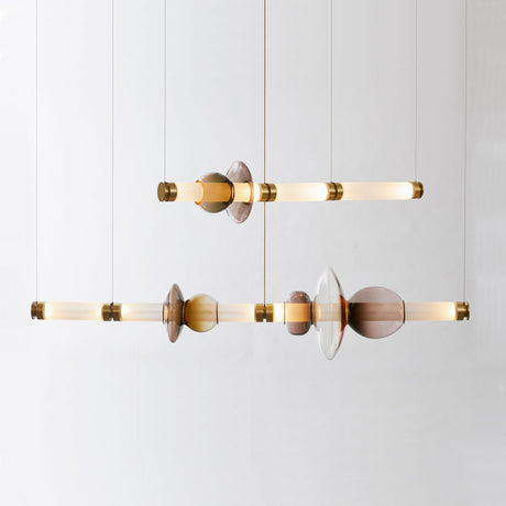 The Luna LED Linear Double Suspension Light - Gold is a modern chandelier with two horizontal rods, highlighted by brass accents and abstract glass elements, and suspended by thin cables against a plain white background.