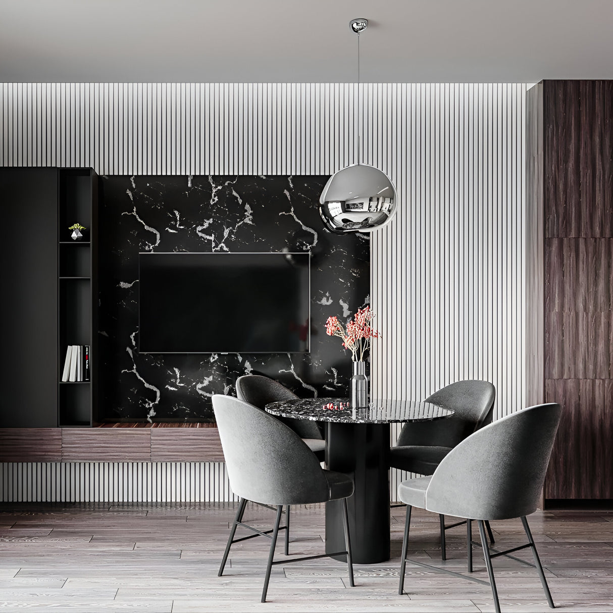 A modern dining area featuring a round black marble table, four gray upholstered chairs, a black marble wall with TV, vertical white paneling, and a Lava Small LED Pendant Light - Silver with adjustable cable lighting above the table and pink flowers in a vase.