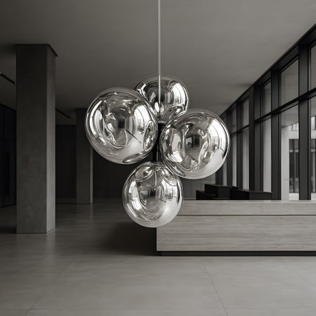 A modern lobby with large windows and minimalist design features the Lava LED 4 Light Chandelier - Silver, casting an ambient glow as it hangs from the ceiling.