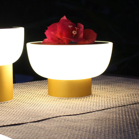 Patio LED Rechargeable Outdoor Table Lamp in gold, bowl-shaped white glowing shade on a slim gold cylinder base, shown lit outdoors with a red flower resting on top beside a second matching lamp.