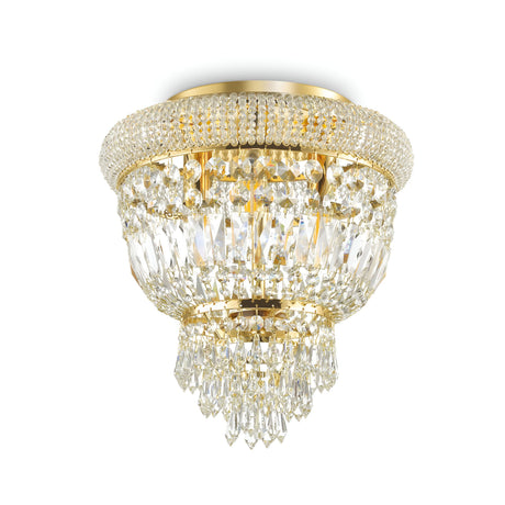 The Emberlit 3 Light Crystal Chandelier - Brass features an opulent design with a circular arrangement and multiple tiers of hanging crystal prisms, offering a sophisticated and shimmering display. Adorned with exquisite crystal elements and affixed to the ceiling, it creates a breathtaking effect.