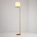 The Vetra 1 Light Opal Glass Floor Lamp features a slim gold stand, an angular base, and a round white opal glass globe lampshade, shown against a plain white background.