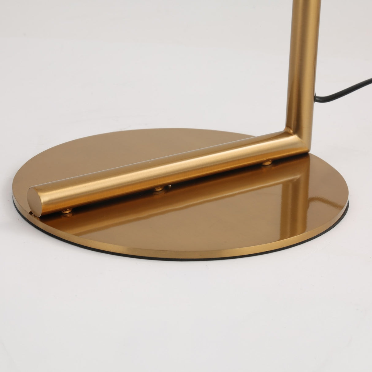 A close-up of the Vetra 1 Light Opal Glass Floor Lamp - Gold shows its circular metallic gold base, cylindrical rod, and black cord, emphasizing the lamp's sleek modern design.