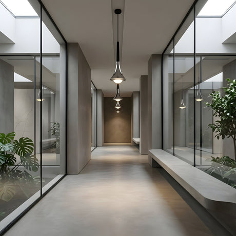 A modern hallway with glass walls, indoor plants, and Droplet LED Pendant Light - Black above long concrete benches creates a minimalist, bright atmosphere.
