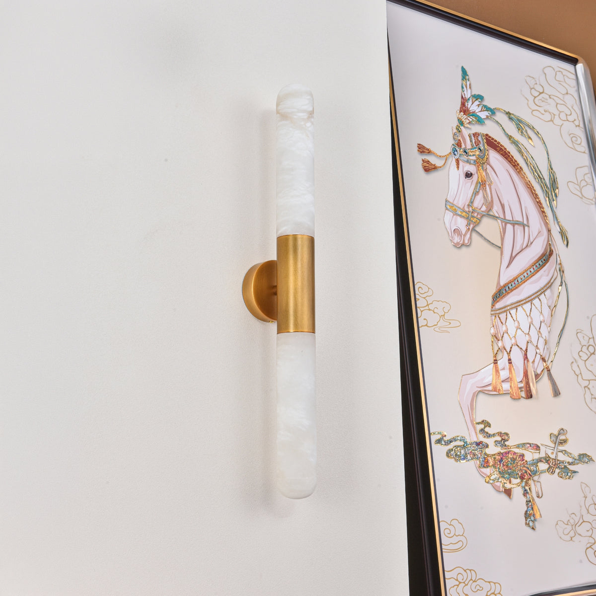 Averin LED Alabaster Wall Light in Brushed Brass, two vertical natural stone columns joined by a brass bracket, mounted beside a framed horse artwork.