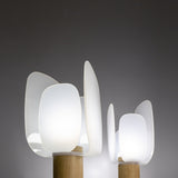 Iselmorne Wooden Table Lamp in white, lit, showing overlapping petal-shaped acrylic panels around a glowing diffuser on a cylindrical oak base, shown in two sizes against a dark background.