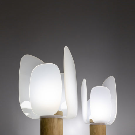 Iselmorne Wooden Table Lamp in white, lit, showing overlapping petal-shaped acrylic panels around a glowing diffuser on a cylindrical oak base, shown in two sizes against a dark background.