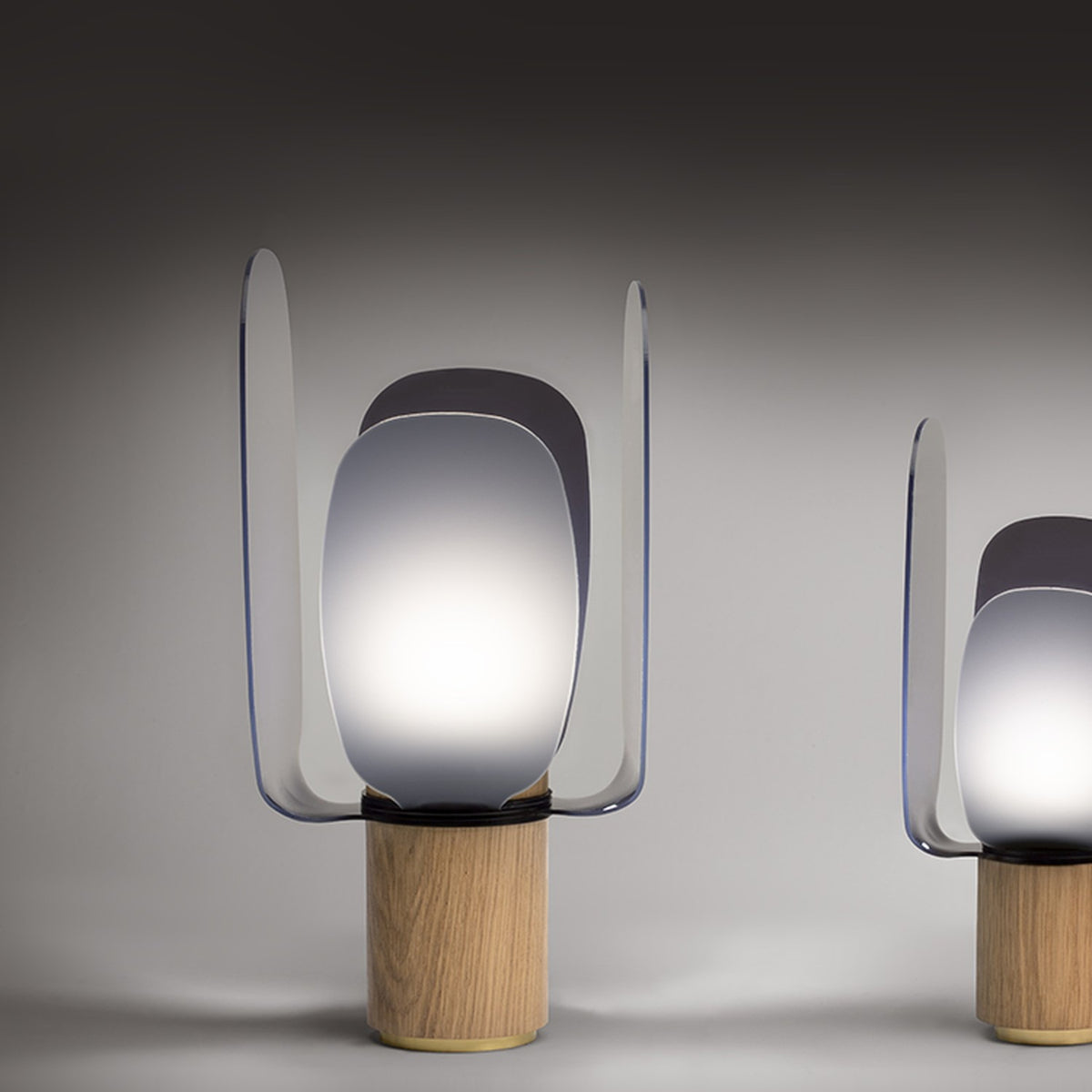 Iselmorne Wooden Table Lamp in black, with four curved smoked acrylic panels around a glowing single light, set on a cylindrical oak base.