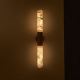 Averin LED Alabaster Wall Light in Brushed Brass, two illuminated vertical alabaster columns joined by a central brass bracket, mounted on a dark wall.