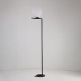 The Vetra 1 Light Opal Glass Floor Lamp in matte black features a minimalist frame and opal glass shade, complementing plain white walls and floors—ideal for contemporary interiors.