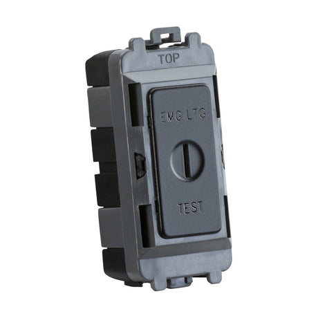 A close-up view showcases the Knightsbridge Grid System's 20AX 2-Way Key Module in a sleek matt black finish. The rectangular electrical switch is labeled "EMG LTG TEST" and features a horizontal slider, marked to indicate the top, combining both elegance and functionality.