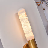Close-up of the Averin LED Alabaster Wall Light in brushed brass, showing the illuminated natural stone column with warm glow and brass bracket fixing.