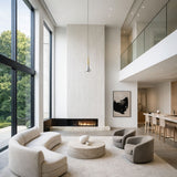 Niori Droplet LED Pendant Light in gold and smoked chrome hanging from a double-height ceiling above a modern living room with curved sofas and fireplace.