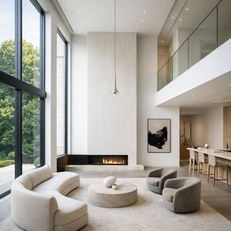 Modern living room with floor-to-ceiling windows, neutral curved sofas and chairs, round coffee table, minimalist fireplace, abstract wall art, open mezzanine with glass railing, and a Droplet LED Pendant Light - Gold accentuating the airy space.