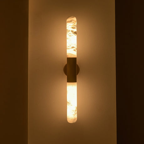 Averin LED Alabaster Wall Light in Brushed Brass, two vertical alabaster columns glowing warm white, joined by a brass centre bracket on a plain wall.