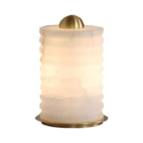 The Aurelior LED Large Ribbed Alabaster Table Lamp – Soft White features a modern design with a cylindrical, frosted white ribbed glass shade and gold accents on the top and base.