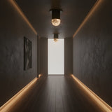 A minimalistic hallway with dark walls, wooden floor, soft baseboard strip lighting, a large frosted window at the end, an abstract painting on the left wall, and two Elara LED Mini Drop Alabaster Semi-Flush Ceiling Lights in Soft White & Matte Black.