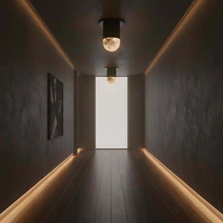 A dimly lit, minimalist hallway with dark walls and floor is illuminated by two Orvani LED Mini Drop Alabaster Semi-Flush Ceiling Lights in Soft White & Matte Black, soft floor-edge lighting, abstract art on the left wall, and a bright frosted window at the end.