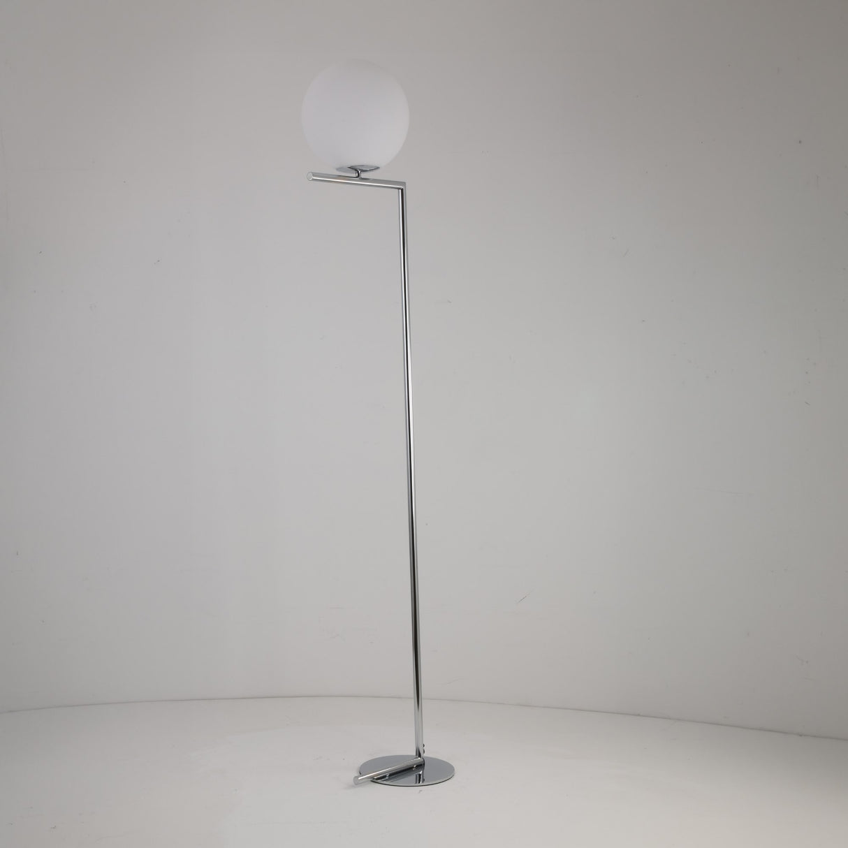 The Vetra 1 Light Opal Glass Floor Lamp in grey features a slim chrome stand and an opal glass sphere shade at the top, offering soft ambient lighting against a plain white background.
